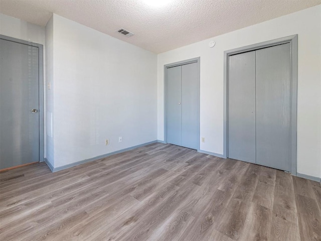 9624 Sugar Hill Dr Unit A & B, Austin, TX 78748 - unfurnished bedroom featuring light wood-style floors, multiple closets, and a textured ceiling