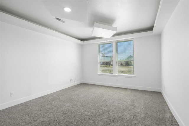 carpeted spare room featuring a raised ceiling, baseboards, and recessed lighting