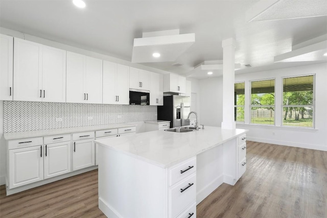 kitchen with stainless steel refrigerator with ice dispenser, a sink, backsplash, light wood finished floors, and baseboards