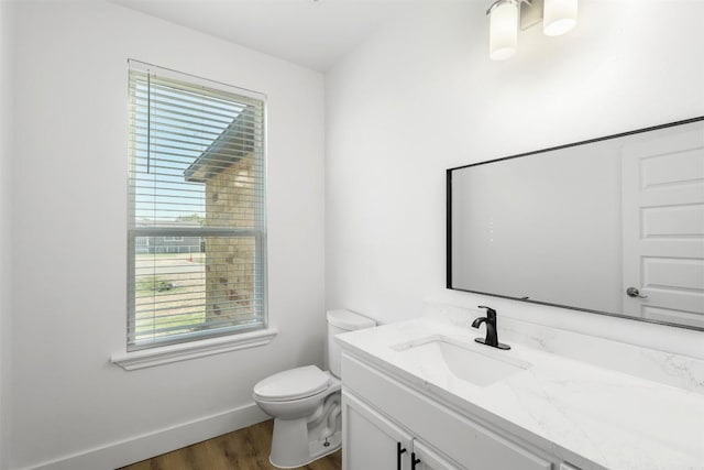 bathroom with wood finished floors, vanity, toilet, and baseboards