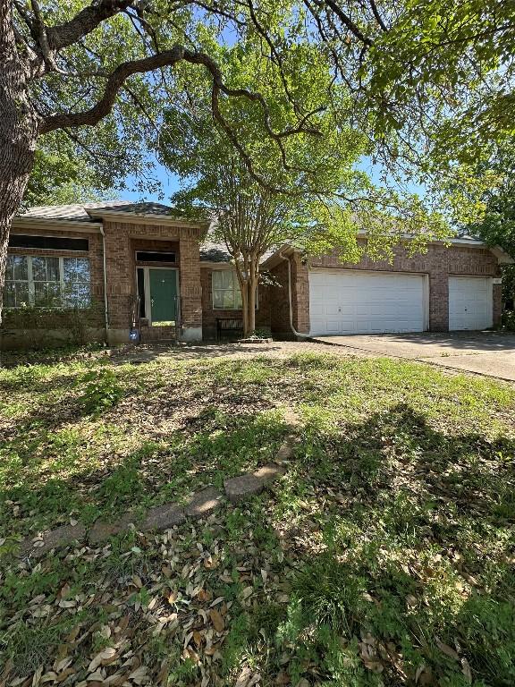view of front of home with a garage, concrete driveway, and brick siding