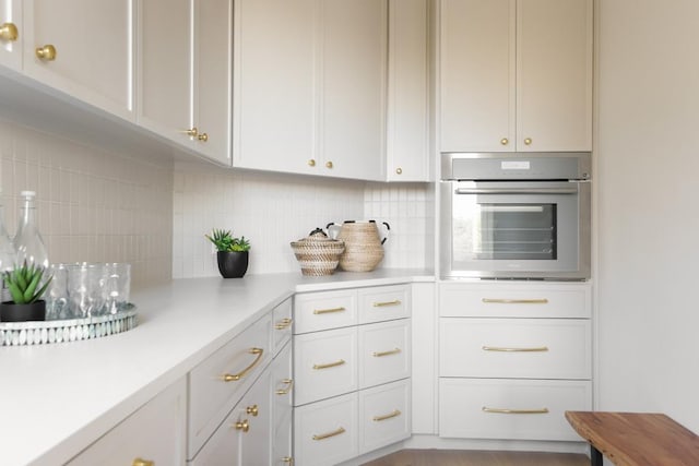 2809 Waterbank Cv, Austin, TX 78746 - kitchen with stainless steel oven, light countertops, backsplash, and white cabinetry