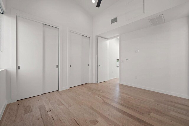unfurnished bedroom with multiple closets, visible vents, and light wood-style floors