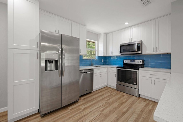 kitchen featuring visible vents, light countertops, a sink, light wood-style floors, and stainless steel appliances