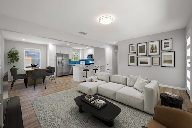 living area with recessed lighting, baseboards, visible vents, and light wood finished floors