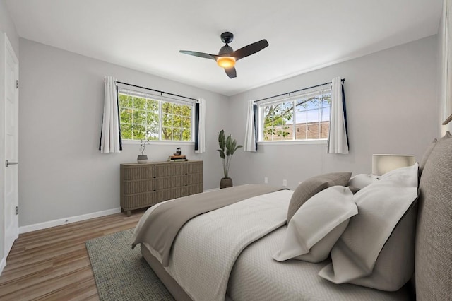 bedroom with a ceiling fan, baseboards, and light wood-type flooring