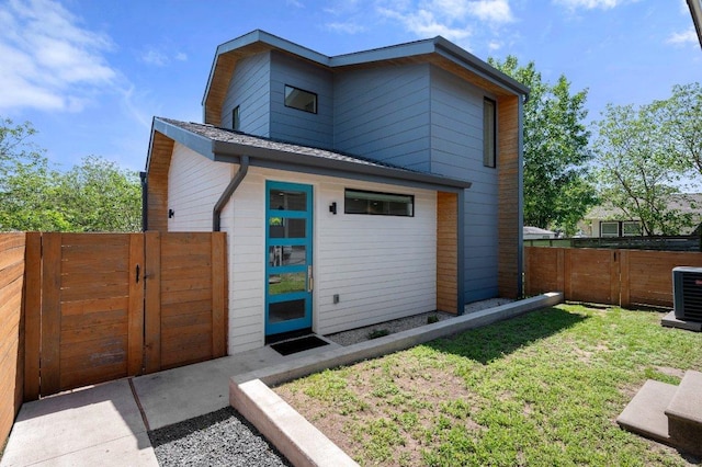 back of house with a lawn, a gate, central AC, and fence