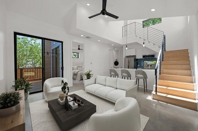 living room featuring recessed lighting, finished concrete flooring, ceiling fan, and stairs
