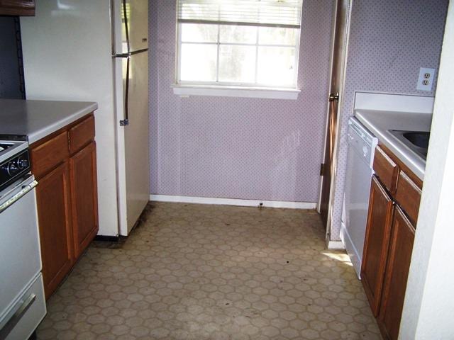 817 Lexington Rd, Elgin, TX 78621 - kitchen with baseboards, light countertops, white appliances, brown cabinets, and dark floors
