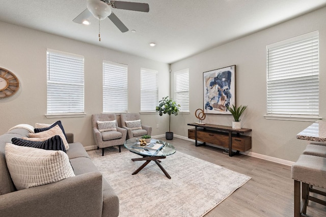 living area with baseboards, light wood-type flooring, a ceiling fan, and recessed lighting