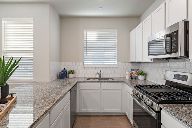 9015 Cattle Baron Path Unit 504, Austin, TX 78747 - kitchen featuring appliances with stainless steel finishes, a sink, white cabinets, and light stone countertops