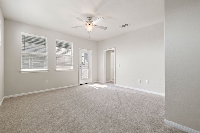 empty room with light colored carpet, visible vents, ceiling fan, and baseboards