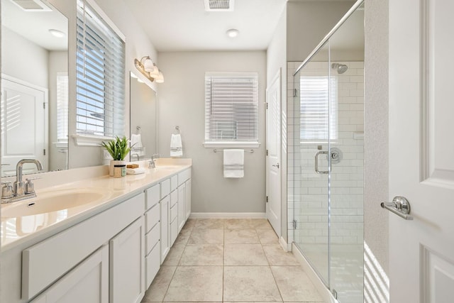 bathroom featuring visible vents, a shower stall, double vanity, and a sink