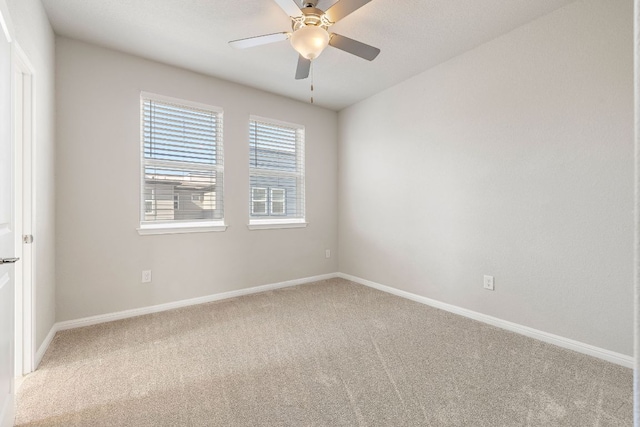 spare room featuring ceiling fan, baseboards, and light carpet