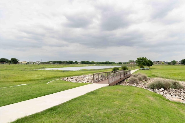 view of property's community with a water view and a lawn