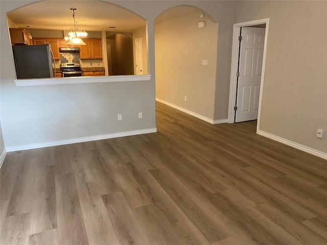 interior space with arched walkways, baseboards, and dark wood finished floors
