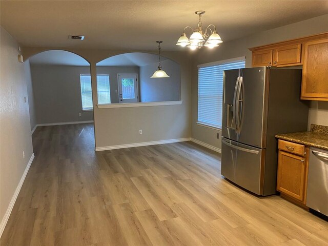 kitchen with visible vents, arched walkways, appliances with stainless steel finishes, light wood-style floors, and brown cabinets