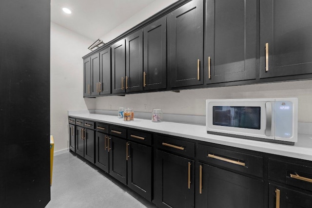 7143 Kc Ranch Ct, Temple, TX 76501 - kitchen with baseboards, light countertops, dark cabinetry, white microwave, and finished concrete floors