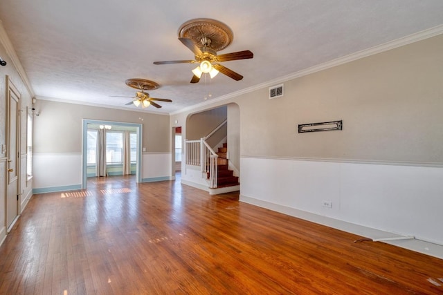 700 S Walnut Ave, Luling, TX 78648 - unfurnished living room with arched walkways, a ceiling fan, wood finished floors, stairway, and crown molding
