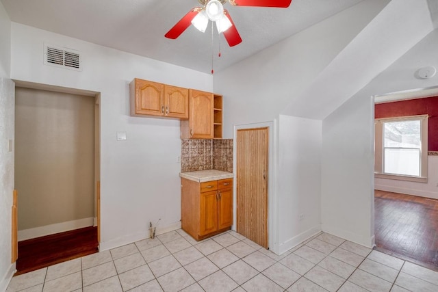 700 S Walnut Ave, Luling, TX 78648 - kitchen with light countertops, ceiling fan, open shelves, tasteful backsplash, and light tile patterned floors
