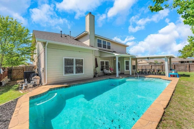 back of property featuring a fenced backyard, a fenced in pool, a patio, and a chimney