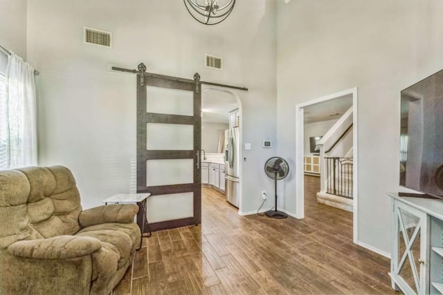 1515 Kothman Dr, Hutto, TX 78634 - living area featuring a high ceiling, wood finished floors, a barn door, and baseboards