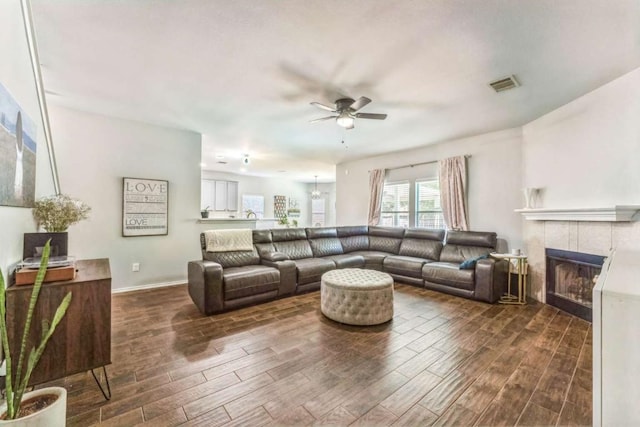 1515 Kothman Dr, Hutto, TX 78634 - living area with dark wood-type flooring, a ceiling fan, a fireplace, and baseboards