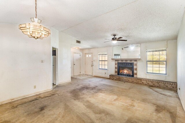 810 San Jacinto St, Lockhart, TX 78644 - unfurnished living room featuring plenty of natural light, carpet floors, ceiling fan, a brick fireplace, and a textured ceiling