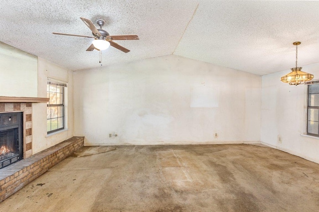 810 San Jacinto St, Lockhart, TX 78644 - unfurnished living room featuring carpet flooring, a lit fireplace, a ceiling fan, a textured ceiling, and vaulted ceiling