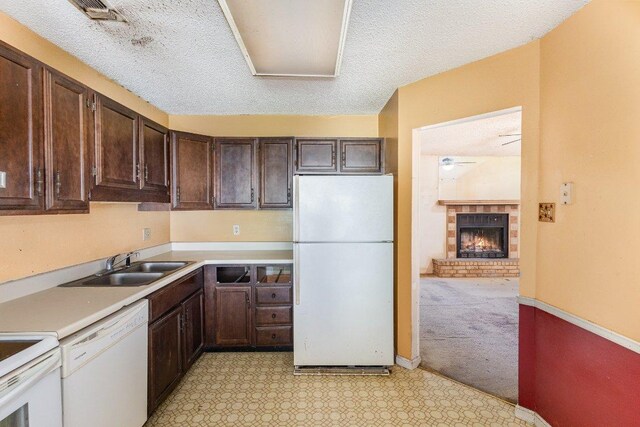 810 San Jacinto St, Lockhart, TX 78644 - kitchen featuring white appliances, dark brown cabinetry, light countertops, light carpet, and a textured ceiling