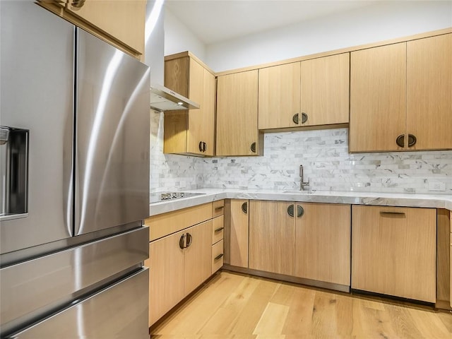 4800 Mondonedo Cv, Austin, TX 78738 - kitchen with stainless steel refrigerator with ice dispenser, wall chimney range hood, light countertops, light wood-style floors, and tasteful backsplash