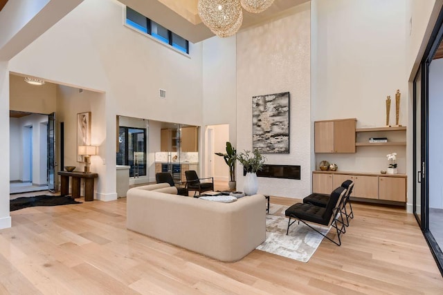 4800 Mondonedo Cv, Austin, TX 78738 - living area with light wood-style flooring, a towering ceiling, a chandelier, and a large fireplace