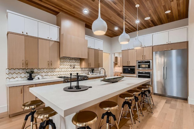 4800 Mondonedo Cv, Austin, TX 78738 - kitchen with appliances with stainless steel finishes, wooden ceiling, a kitchen breakfast bar, light wood-style flooring, and backsplash