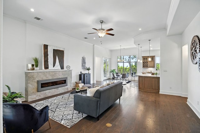5200 Patagonia Pass, Austin, TX 78738 - living area featuring a ceiling fan, a tile fireplace, crown molding, recessed lighting, and dark wood-type flooring