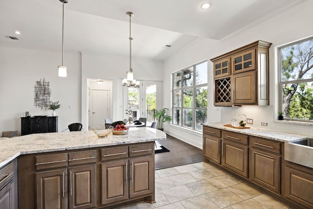 5200 Patagonia Pass, Austin, TX 78738 - kitchen with a chandelier, hanging light fixtures, glass insert cabinets, light stone counters, and recessed lighting