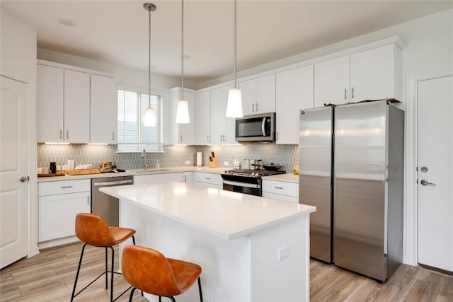 kitchen with appliances with stainless steel finishes, a center island, light wood-style flooring, and a sink
