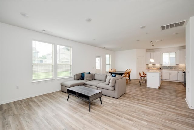 living room featuring visible vents, light wood finished floors, and plenty of natural light