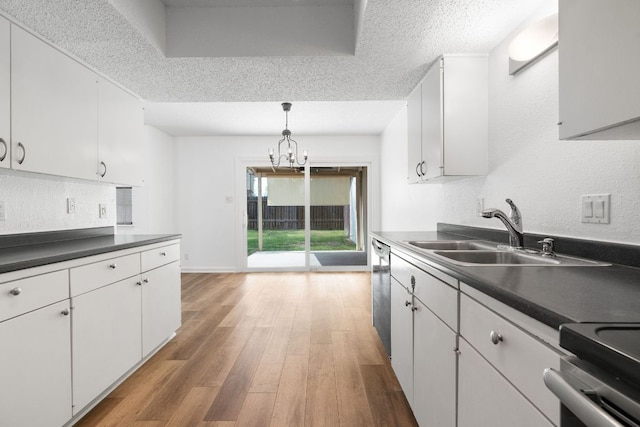8902 Trone Cir Unit A, Austin, TX 78758 - kitchen featuring stainless steel appliances, light wood-style floors, dark countertops, a chandelier, and white cabinetry