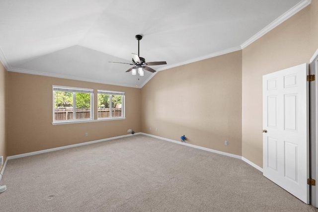 carpeted empty room featuring vaulted ceiling, baseboards, crown molding, and a ceiling fan