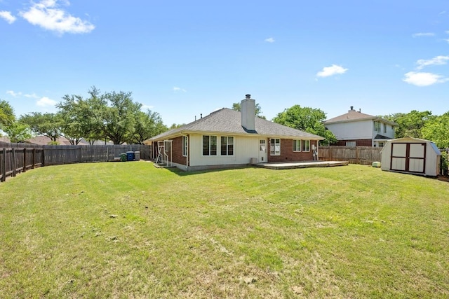 rear view of house featuring a yard, an outbuilding, a shed, and a fenced backyard