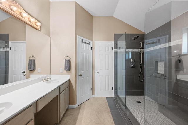 full bathroom featuring a sink, a tile shower, double vanity, and lofted ceiling