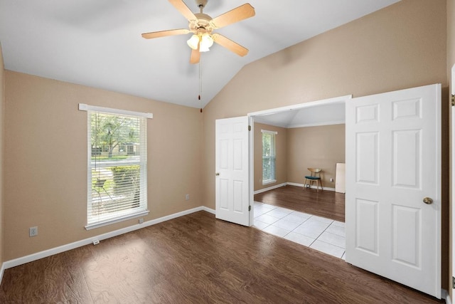 empty room featuring baseboards, ceiling fan, wood finished floors, and lofted ceiling