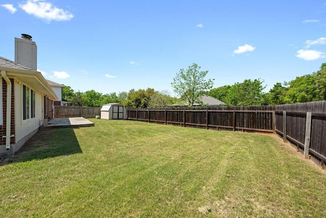 view of yard with a storage unit, a fenced backyard, and an outbuilding