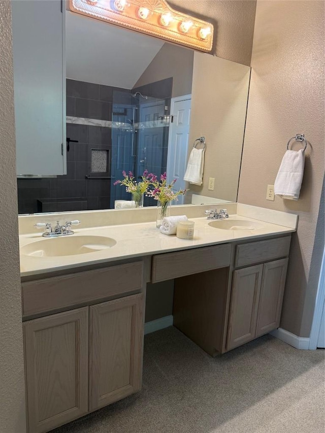 bathroom with a sink, a tile shower, and double vanity