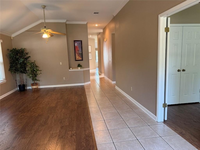 hall with visible vents, crown molding, baseboards, light wood-style flooring, and vaulted ceiling