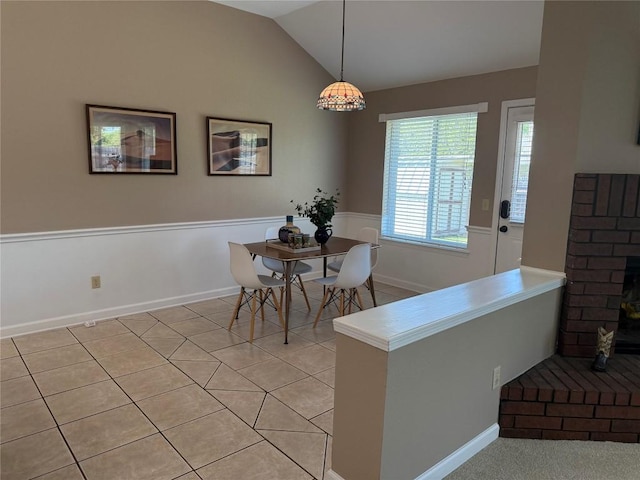 dining space with baseboards, light tile patterned flooring, and lofted ceiling