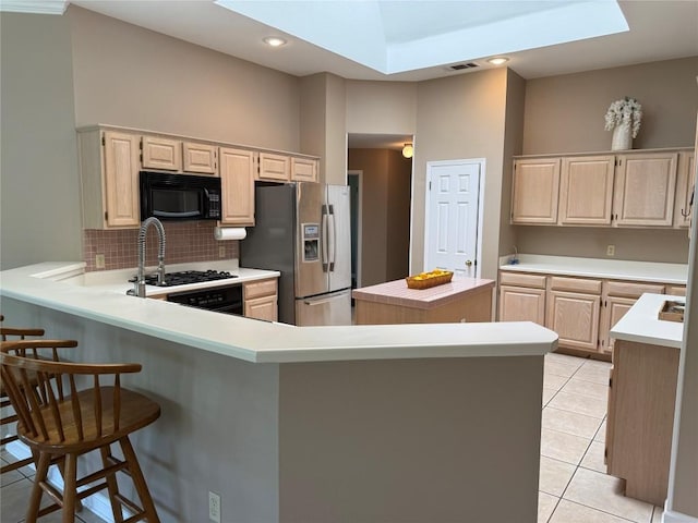 kitchen featuring black microwave, light countertops, light tile patterned floors, stainless steel refrigerator with ice dispenser, and a skylight