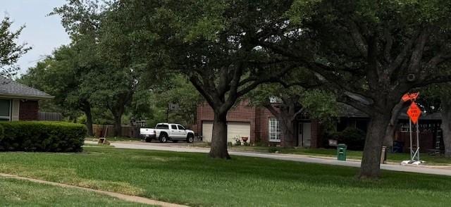 view of home's community featuring a yard and concrete driveway