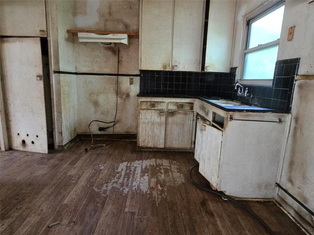 kitchen with dark countertops, dark wood-style floors, decorative backsplash, and a sink