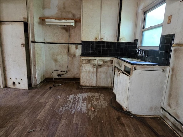 kitchen with dark countertops, dark wood-style floors, decorative backsplash, and a sink